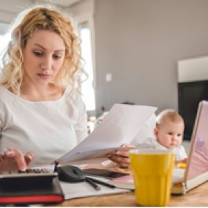photo mother working on budget with baby watching