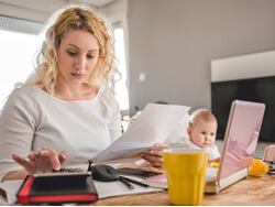 photo mother working on budget with baby watching